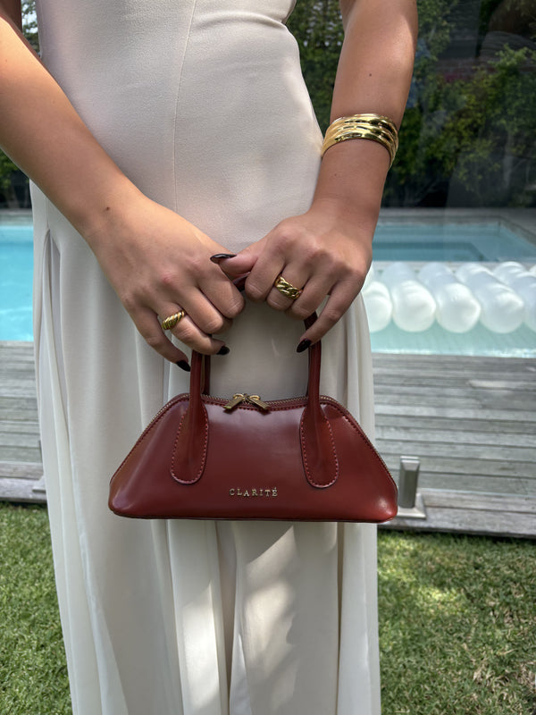 Person holding a red handbag with a blurred outdoor background