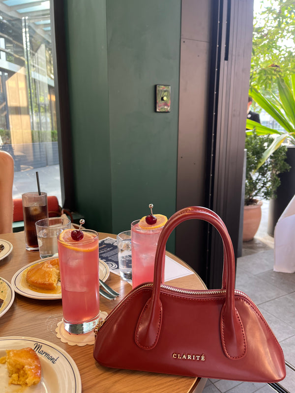 Red handbag on a table with drinks and pastries in a cafe setting