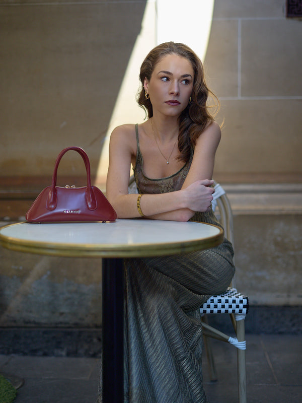 Woman sitting at a table with a red handbag in an indoor setting